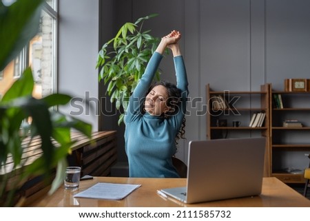 Happy businesswoman warming up body and muscles at workplace, feeling satisfied with work done, smiling female employee resting from computer screen. Well-being, productivity and happiness at work