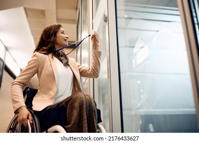 Happy Businesswoman In Wheelchair Using An Access Card To Enter In The Office. Copy Space.