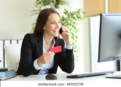 Happy businesswoman working buying on line with credit card and calling customer service at office - Powered by Shutterstock