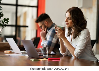 Happy businesswoman working on laptop. Portrait of beautiful businesswoman drinking coffee