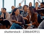 Happy businesswomen communicating during an education event in conference hall. 