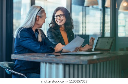 Happy businesswomen having a meeting in office. Two business colleagues discussing business matters. - Shutterstock ID 1180857355