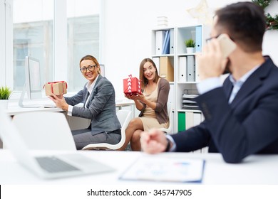 Happy Businesswomen Showing Christmas Gifts To Colleague In Office