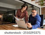 Happy busy executive people working together in office. Female manager showing financial results to colleague at work. Two professional team business man and woman using laptop at corporate meeting.