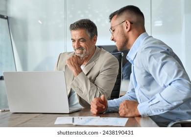 Happy busy professional team of two business men executive having discussion, male partners working using laptop looking at computer analyzing online tech data at work in office sitting at desk. - Powered by Shutterstock