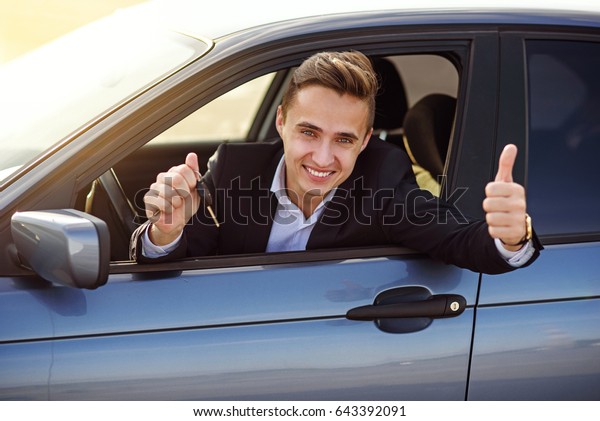 Happy buyer\
holding car keys inside his new\
vehicle