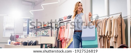 Happy byer with shopping bags standing in showroom, banner 