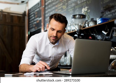 Happy Cafe Manager Counting Recipes With Laptop