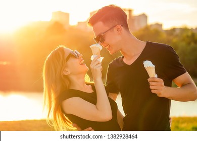 happy californian couple in love in summer park. beautiful woman and handsome man eat ice cream in a waffle horn cone at sunset on the beach. cool photosession photoshoot of young family