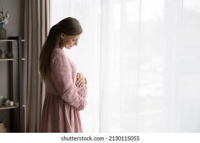 Happy calm expecting mom wearing natural cloth for pregnant touching, hugging, caressing baby bump with love, tenderness, peace, looking at big stomach, smiling. Expectant woman enjoying pregnancy