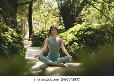 Happy calm mindful young Hispanic woman meditating doing yoga breathing exercises with eyes closed feeling peace of mind, mental balance sitting in lotus pose in green nature tropical park outdoors. - Powered by Shutterstock