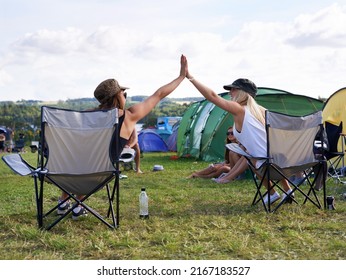 Happy campers. Rearview shot of two friends giving each other a high five at an outdoor festival. - Powered by Shutterstock