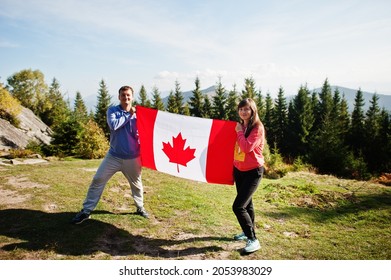 Happy Canada Day. Couple With Large Canadian Flag Celebration In Mountains. 