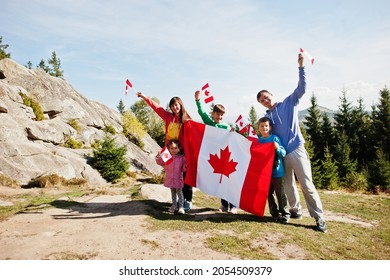 Happy Canada Day. Family with large Canadian flag celebration in mountains. 