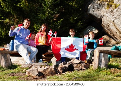 Happy Canada Day. Family With Large Canadian Flag Celebration In Mountains. 