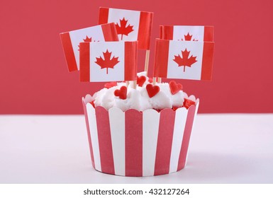 Happy Canada Day Party Cupcake With Maple Leaf Flags On A White Wood Table Against A Red Background. 