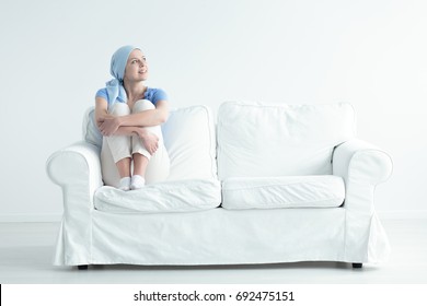 Happy Cancer Patient Feeling Relieved And Holding Her Knees On A White Sofa