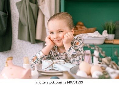 Happy Candid Little Kid Four Year Old Girl Bored With Hands Fists In Face Ready And Waiting For Lunch Or Dinner Of Springtime Easter Holiday At Home Kitchen Decorated Festive Table With Easter Eggs