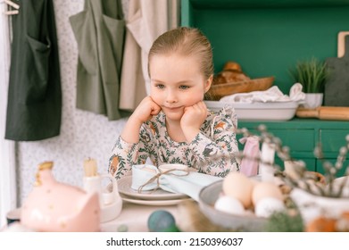 Happy Candid Little Kid Four Year Old Girl Bored With Hands Fists In Face Ready And Waiting For Lunch Or Dinner Of Springtime Easter Holiday At Home Kitchen Decorated Festive Table With Easter Eggs