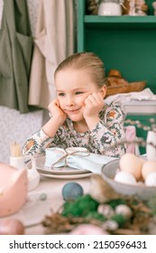 Happy Candid Little Kid Four Year Old Girl Bored With Hands Fists In Face Ready And Waiting For Lunch Or Dinner Of Springtime Easter Holiday At Home Kitchen Decorated Festive Table With Easter Eggs