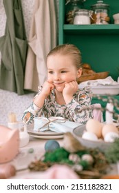 Happy Candid Little Kid Four Year Old Girl Bored With Hands Fists In Face Ready And Waiting For Lunch Or Dinner Of Springtime Easter Holiday At Home Kitchen Decorated Festive Table With Easter Eggs