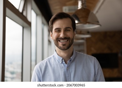 Happy Candid Young Caucasian Man Looking At Camera, Holding Video Call Conversation Or Passing Remote Job Interview. Portrait Of Smiling Male Employee Worker Leader Posing In Modern Office Room.