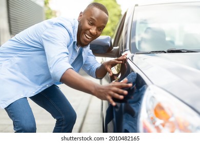 Happy Car Buyer, New Car Owner Concept. Portrait Of Excited Young African American Guy Touching His New Luxury Automobile After Purchase In Dealership Showroom. Selective Focus