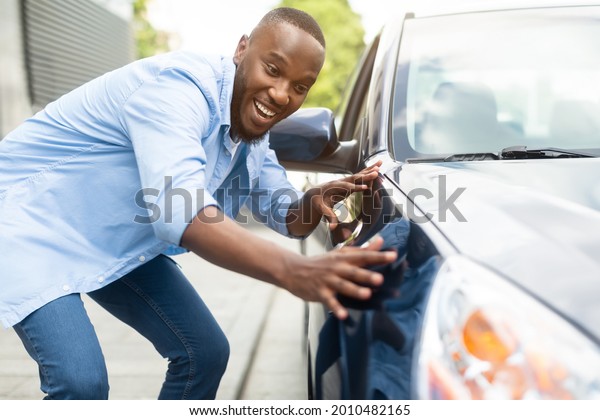 Happy Car Buyer, New\
Car Owner Concept. Portrait Of Excited Young African American Guy\
Touching His New Luxury Automobile After Purchase In Dealership\
Showroom. Selective Focus