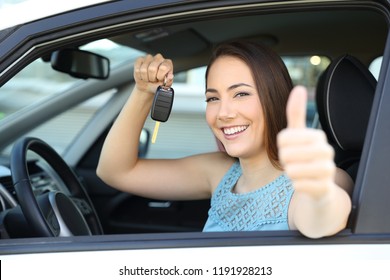 Happy car owner looking at camera holding a key gesturing thumbs up