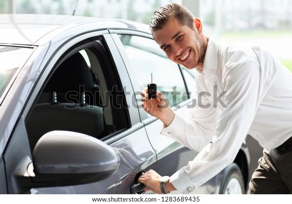 Happy\
car owner is showing thumbs up and his new car\
key