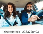 Happy car owners middle eastern husband and wife enjoying automobile ride together on weekend, sitting on front passengers seats with safety belts on, smiling at camera