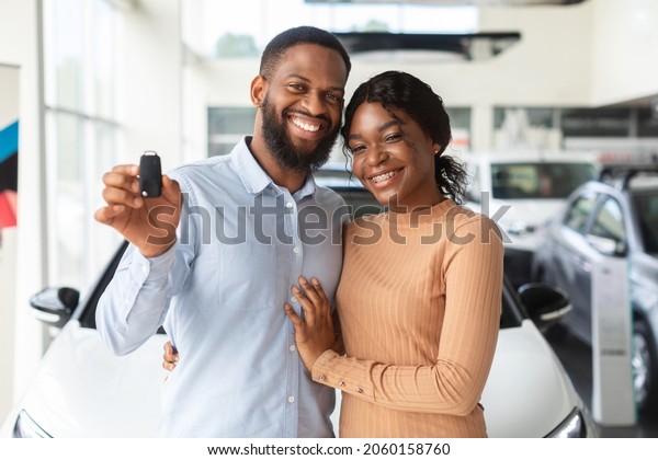 Happy\
Car Owners. Portrait Of Young Black Couple With Automobile Keys In\
Hands Posing In Modern Dealership Center After Purchasing Their Own\
Vehicle, African American Family Smiling At\
Camera