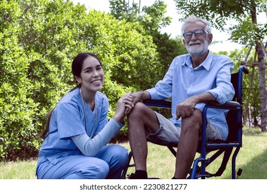 Happy care taker with wheelchair senior man in garden, Old disabled man sitting on wheelchair with friendly young Asian caregiver in nursing home park during rehabiliation, elderly man on wheelchair - Powered by Shutterstock