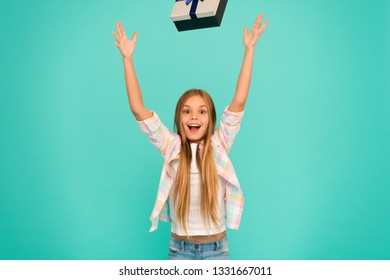 Happy and carefree. Small child tossing gift box up. Little shopaholic with present wrapped in box. Small girl after shopping for gift. Cute shopper enjoy doing a little shopping. Foto Stock