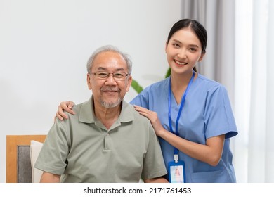 Happy Caregiver And Elderly Patient Smile And Looking Camera Nursing At Home. Asian Senior Man And Doctor Giving Care And Empathy To Patient Or Retirement In Homecare Service. Elderly Care Concept