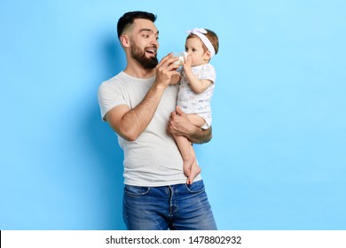 Happy Caring Dad Looking At Adorable Baby Drinking Milk From Bottle. Close Up Photo. Love, Family, Relationship Concept. Studio Shot