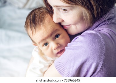 Happy caring mother holding baby boy in the bedroom. The concept of the tenderness of motherhood and family values