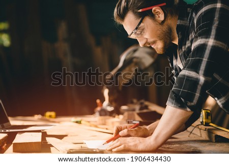 Happy Carpenter smiling to sketch design wooden furniture in wood workshop professional look high skill real authentic handcrafted working people.