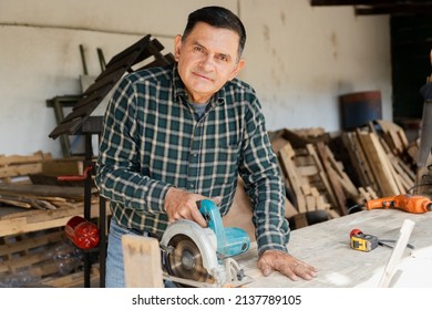 Happy carpenter working with carpentry tools - Smiling Hispanic man doing carpentry in a wood workshop