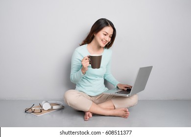 Happy Casual Beautiful Asian Woman Working On A Laptop Sitting On Floor At Home.