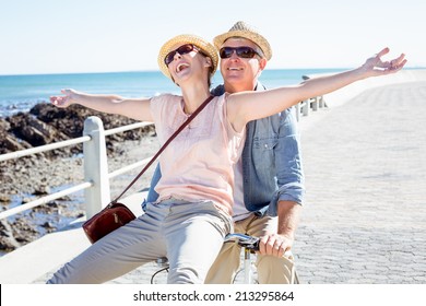 Happy Casual Couple Going For A Bike Ride On The Pier On A Sunny Day