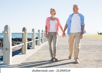 Happy casual couple walking by the coast on a sunny day