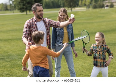 Happy Casual Family Playing Badminton In Park At Daytime