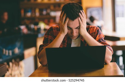 Happy Casual Man Using Smartphone And Laptop Computer In Cafe Under Stress And Preparing For Exams