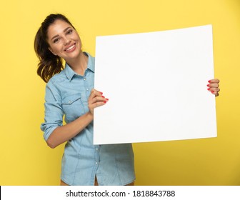 Happy Casual Woman Smiling And Holding Blank Newspaper While Standing On Yellow Studio Background