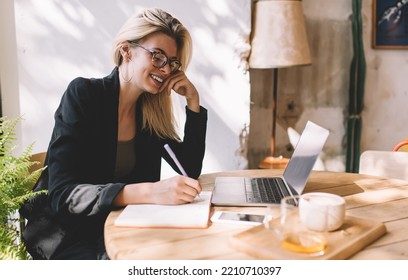 Happy Caucaisan Woman In Spectacles For Provide Vision Correction Enjoying Time For Organization Planning On Distance Job, Cheerful Skilled Freelancer With Modern Laptop Computer Writing In Textbook