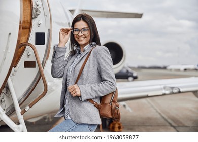Happy caucasian beautiful dark hair businesswoman is boarding a private jet
