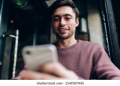 Happy Caucasian blogger enjoying mobile communication during leisure time using 4g wireless for browsing content text, smiling hipster guy checking email while messaging via cellphone technology