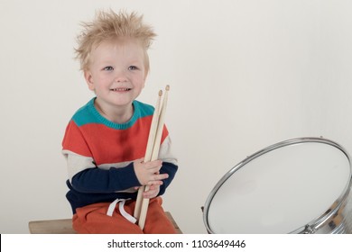 Happy Caucasian  Blonde With Drumstick. Drummer Play On A New Drum Kit. Parents Bought A Drum Box For Training. Child In Bright Clothes With New Chopsticks In Hands Happy At Home. Bright Emotions 