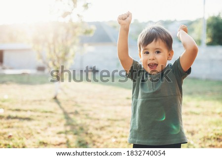 Happy caucasian boy gesturing a win is celebrating childrens day outside in the backyard smiling at camera